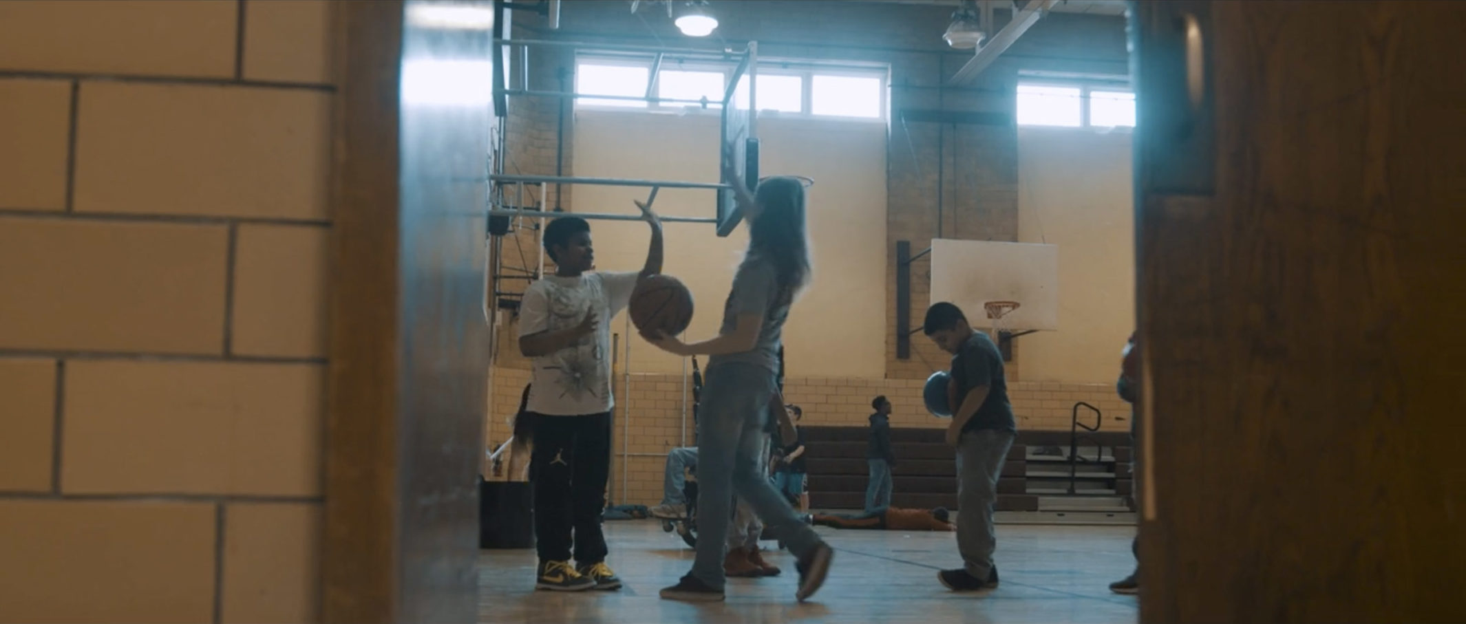 Two students about to high-five in a school gym.