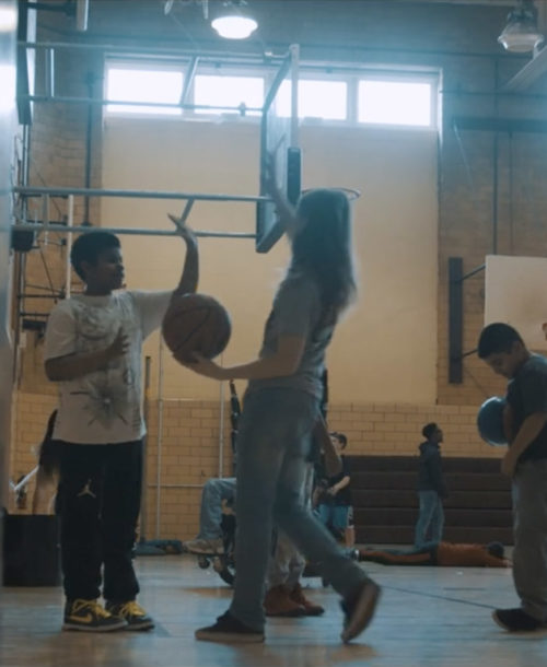 Two students about to high-five in a school gym.