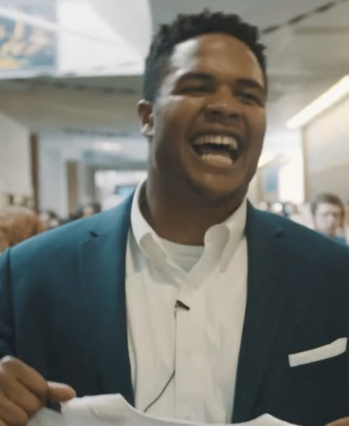 Eddie Yarbrough smiling as he walks down the hallway of his high school.