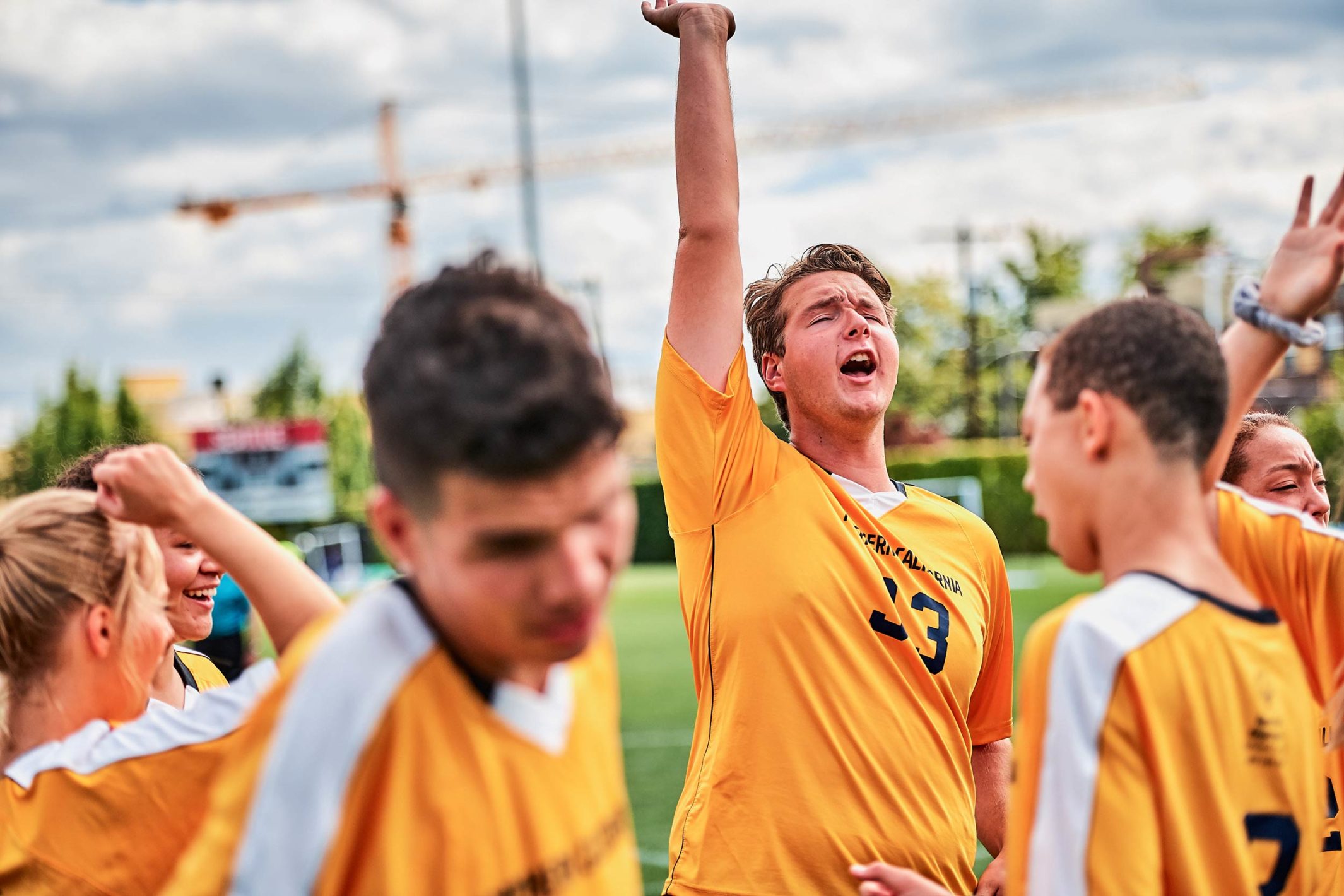 Young man with his team reaching his hand up in the air in triumph.