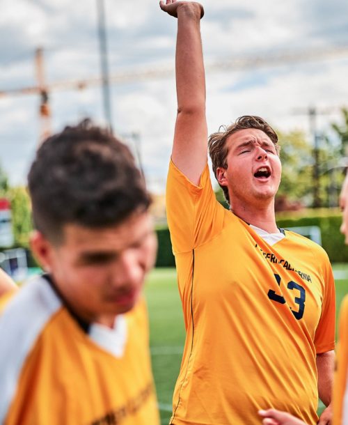 Young man with his team reaching his hand up in the air in triumph.