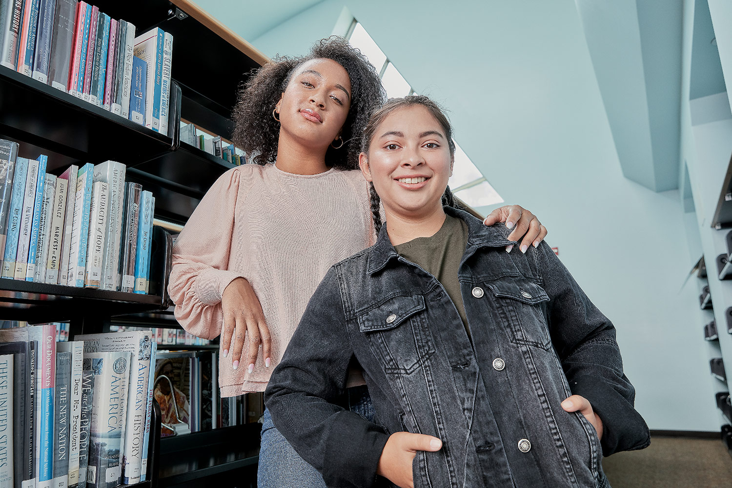 Two students standing in front of lockers. The male student is looking at the camera and the female student is looking at the male student.