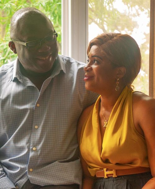 Claude and Catherine Dayas-Tokoto sitting in their home looking into each other's eyes.