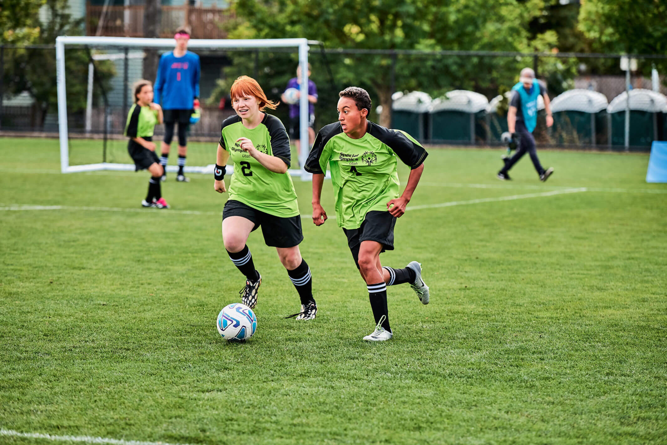 Two soccer players working together to dribble the ball down the field.