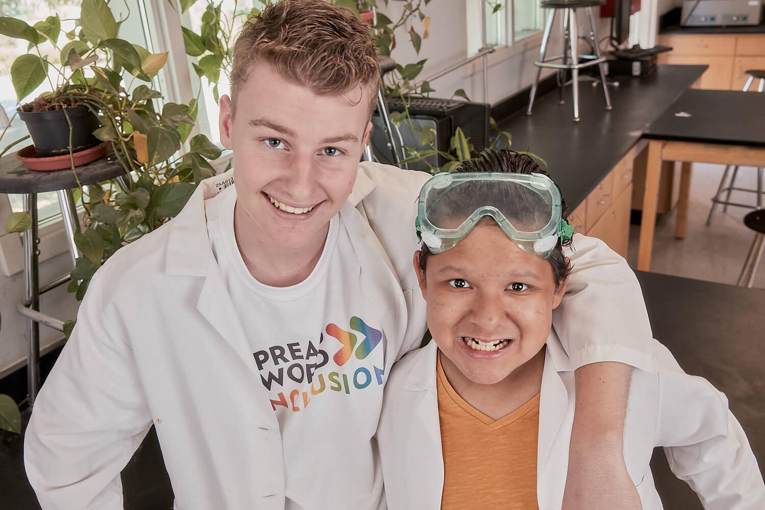 Students posing in a lab. One is wearing a Spread the Word t-shirt.