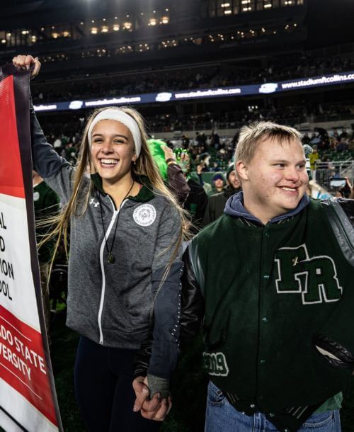 Two members of an SO College waiving while holding their National Banner.