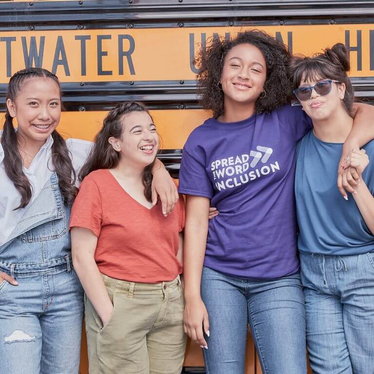 Group of students posing in front of a school bus.