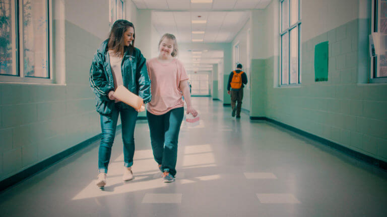 Emily and Kate walking down a school hallway.