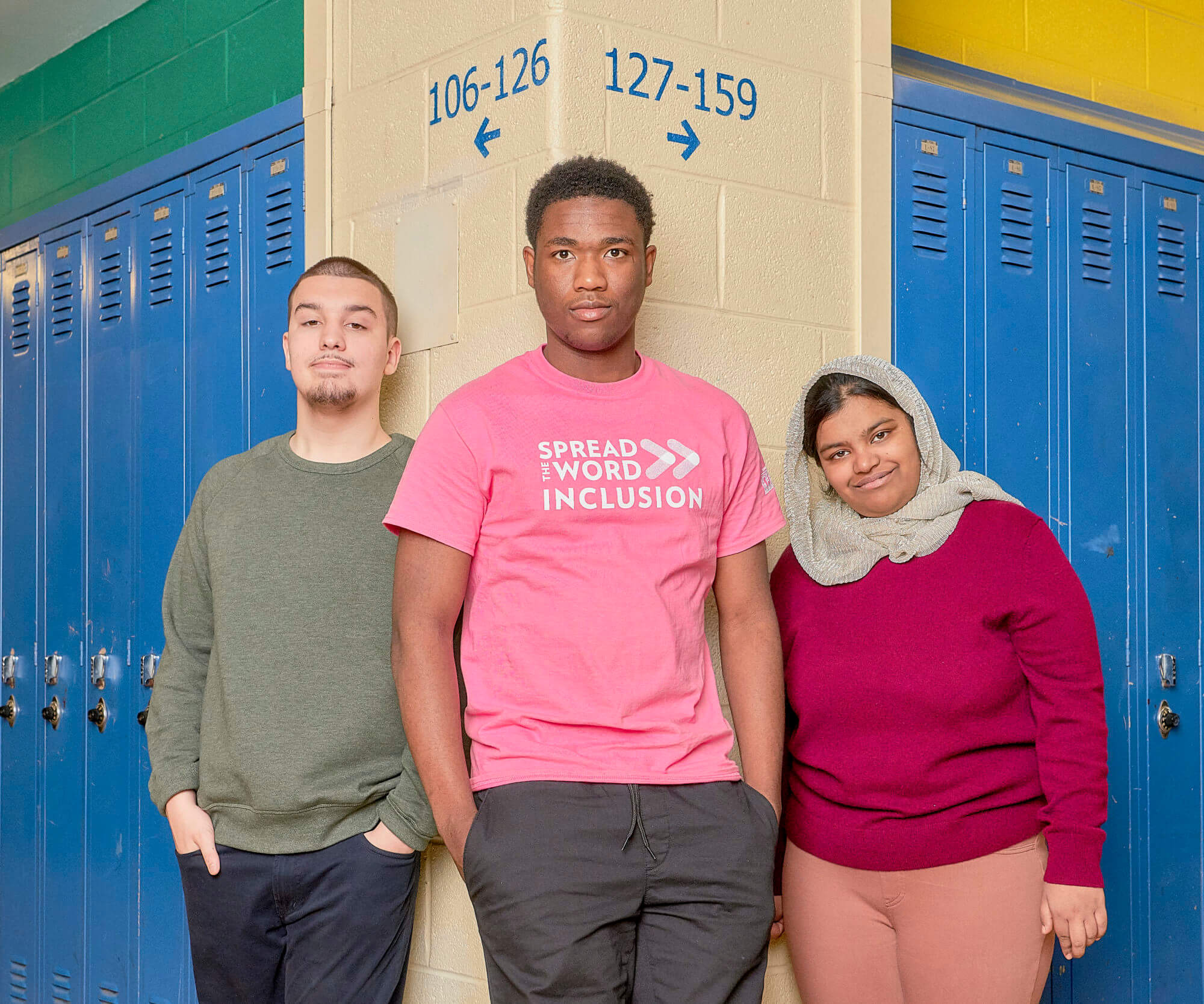 Three students standing alongside a row of lockers.