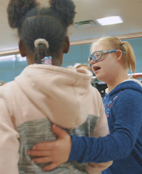 A student from Copper King Elementary puts her arm around another student.