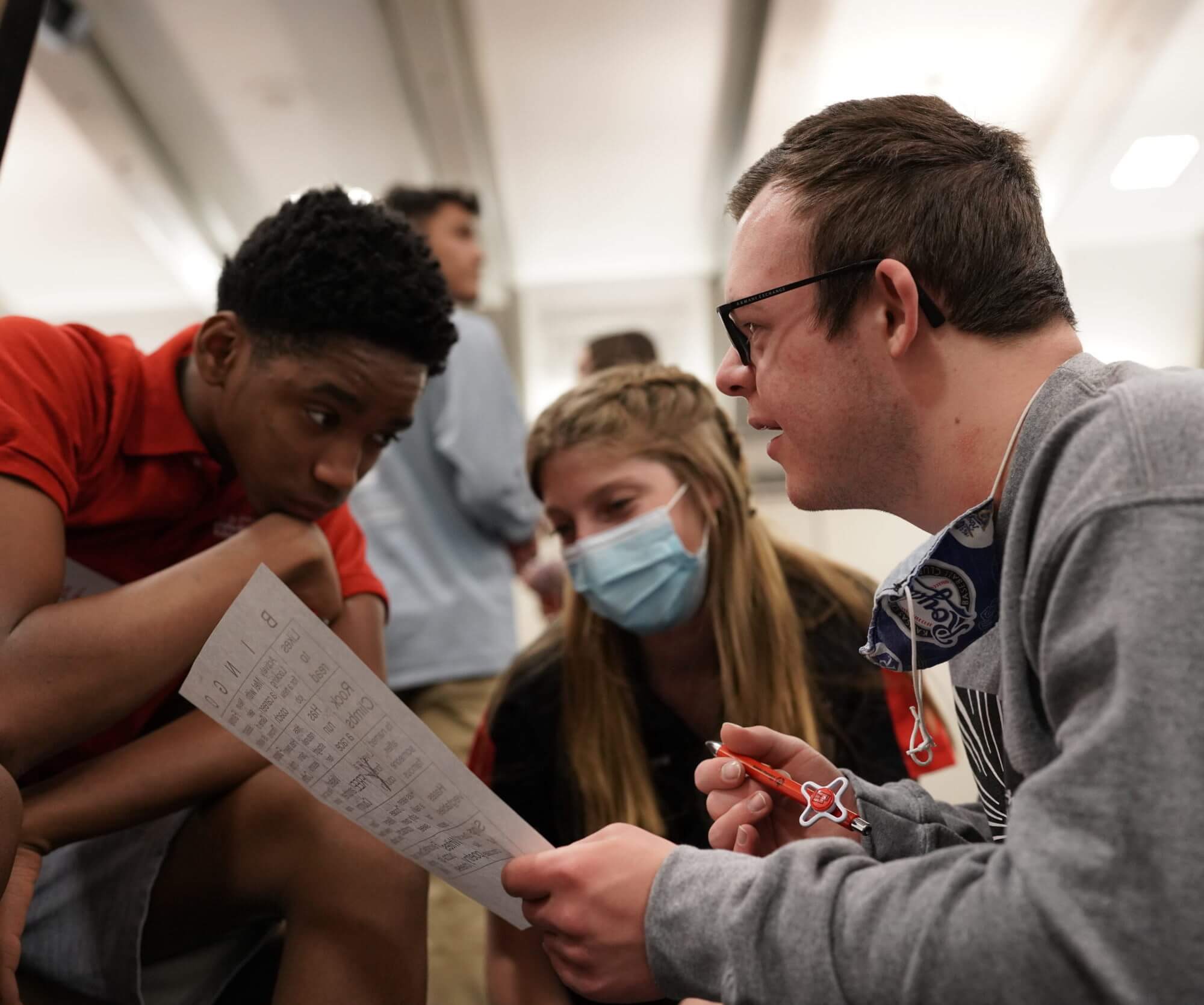 U.S. Youth Ambassadors Isaiah and Daniel working with a youth leader from Special Olympics Utah. They are crouched around a piece of paper.