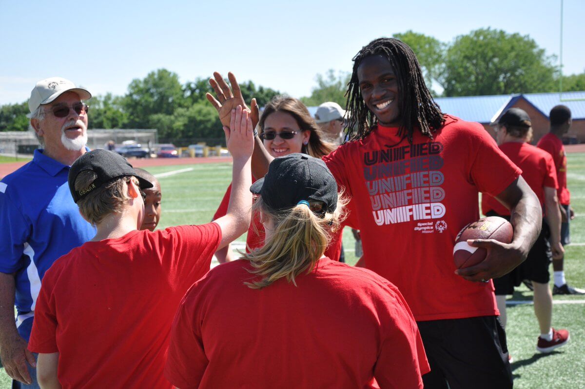 Former NFL running back Jamaal Charles gives high-fives to a group of Special Olympics athletes.