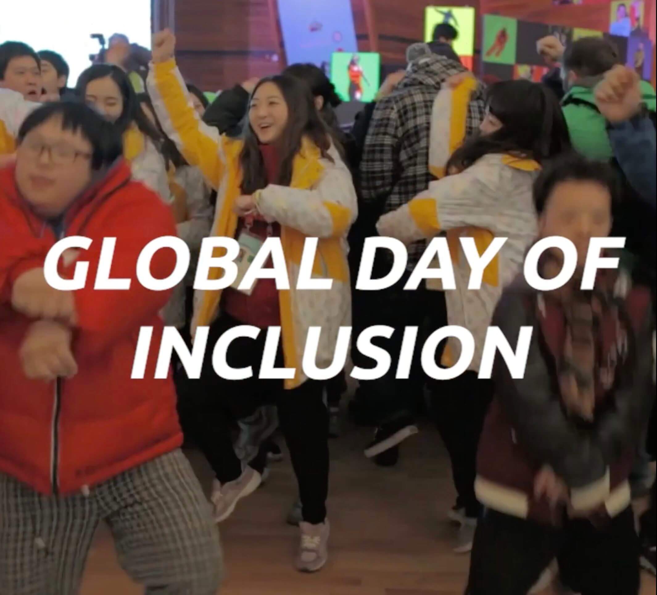 The image reads 'Global Day of Inclusion' and is in white text in front of many people dancing