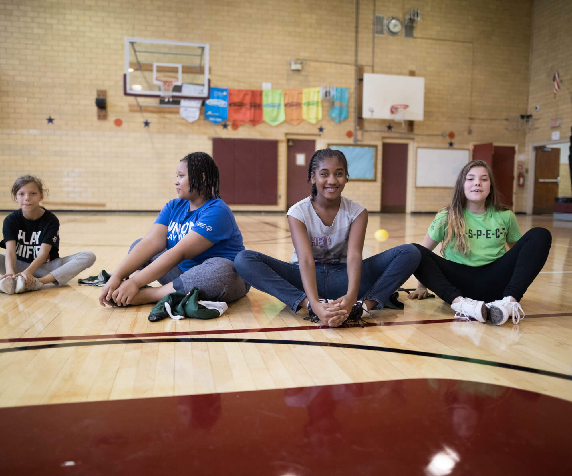 A group of students with and without disabilities doing the butterfly stretch and smiling for the camera.