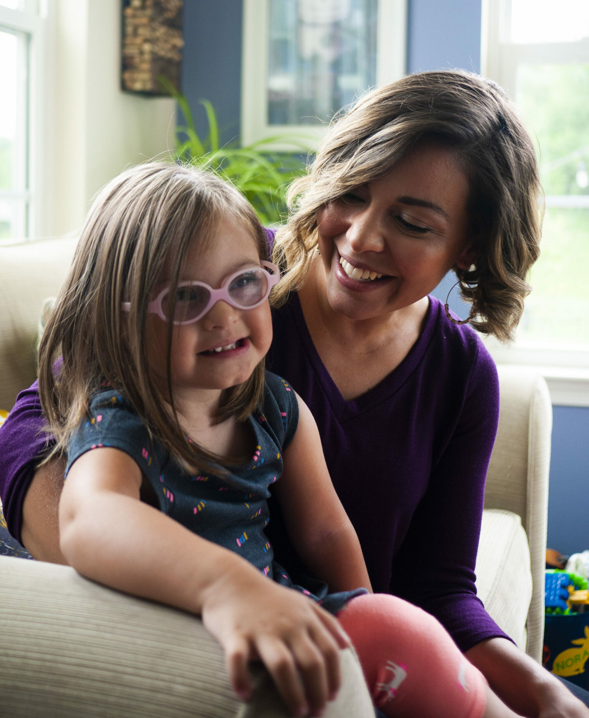 Nora, a girl with Down syndrome sitting with her mother Kim on the couch.
